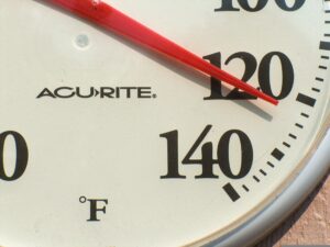 A photograph of an outdoor thermometer reading 122 degrees Fahrenheit