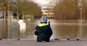 Photograph of a child sitting and staring out at a flooded area