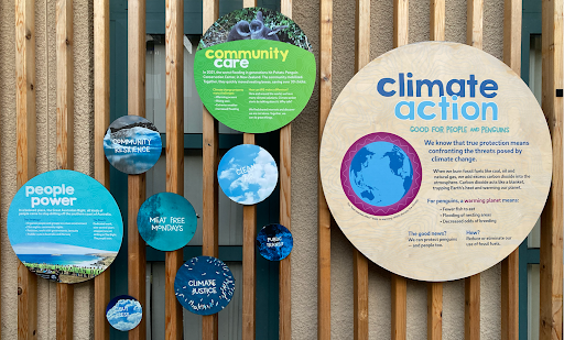 An image of the “Climate Action Wall”, which displays several circular wall panels with text emphasizing solutions, collective action, understanding cause and effect, and talking about climate.