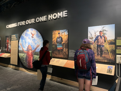 Two people standing and looking at the Climate Solutions exhibition at The Wild Center, New York.